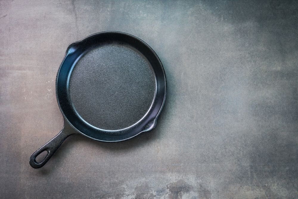 A cast iron pan for cooking lies flat on a dark background, representing one of the options for nontoxic kitchen products.
