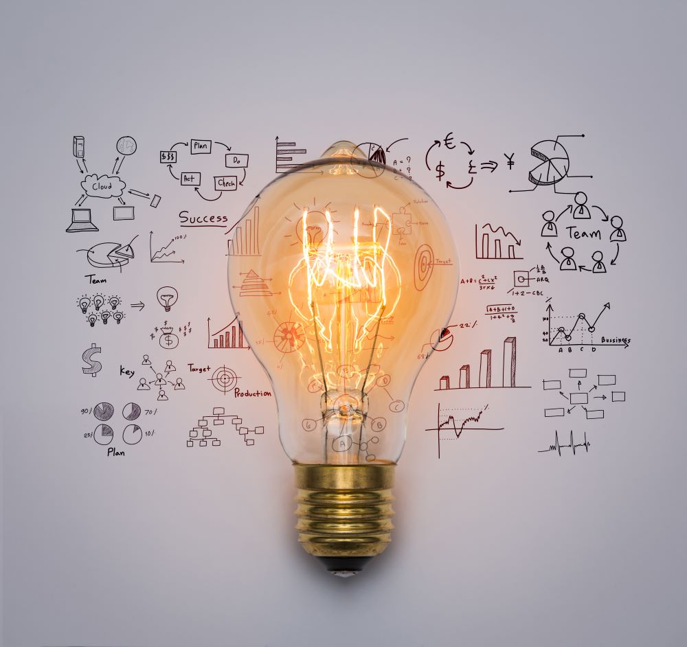 A lightbulb is lit with with warm light against the background of some sketches of graphs and tables in pen, perhaps a volunteer using their expert skillset to plan how to help a nonprofit or work with a nonprofit.