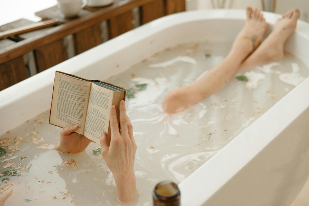 Serene moment of a woman enjoying a calming bath surrounded by candles, reading a book for relaxation and self-care. Peaceful ambiance with soothing vibes.